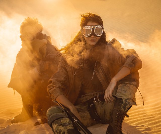 Women in mask in desert, post-apocalyptic setting.